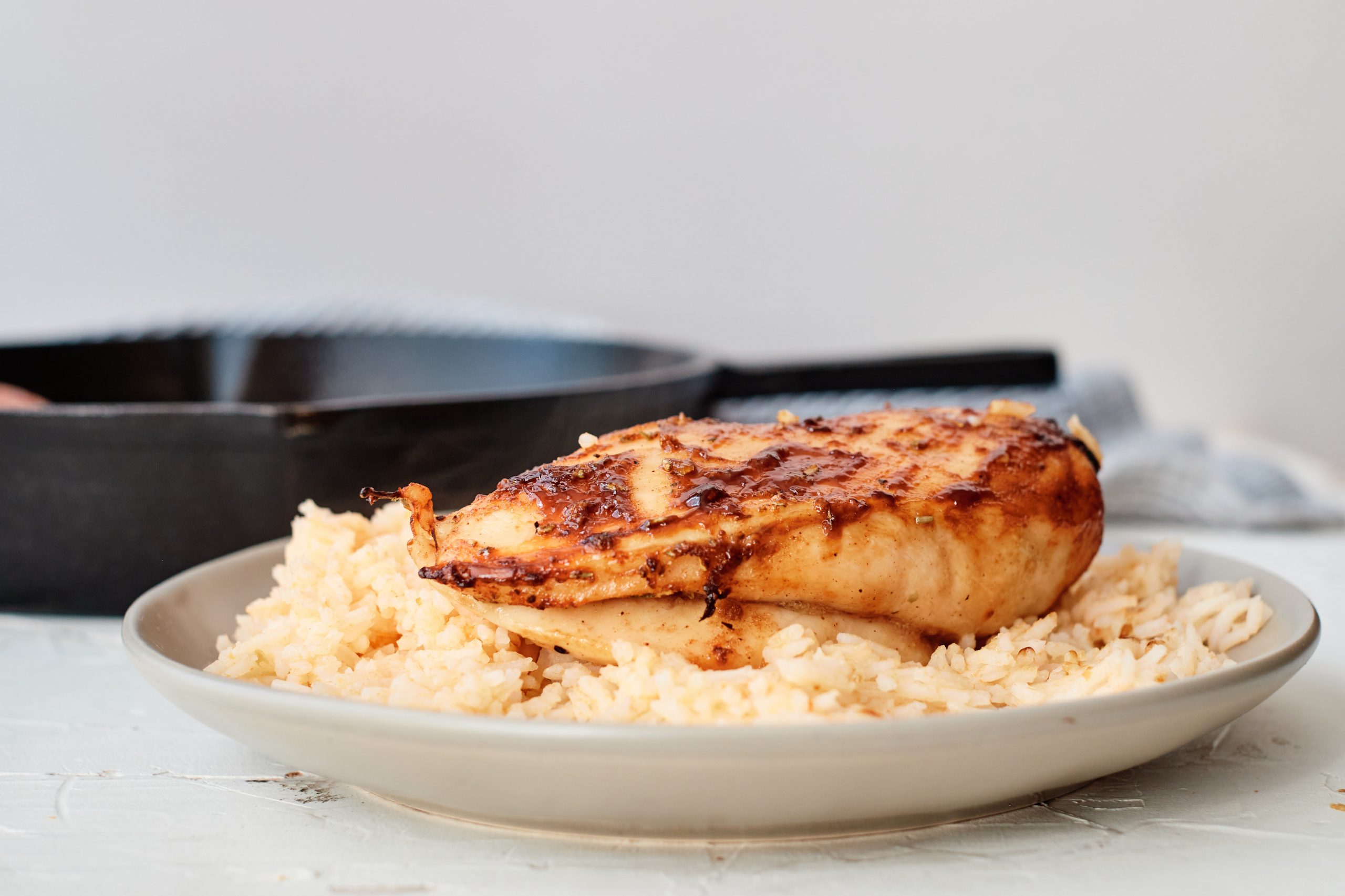 Cuban-Style Chicken on a bed of rice on a plate with a cast iron skillet in the background