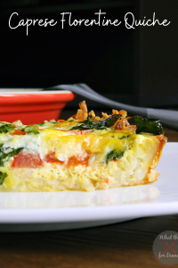 An unclose photo of a slice of Caprese Florentine Quiche on a white plate with a red serving dish and spatula in the background