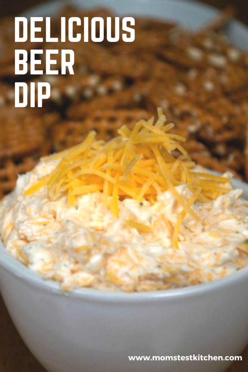 a bowl of delicious beer dip topped with shredded cheddar cheese and served with pretzels