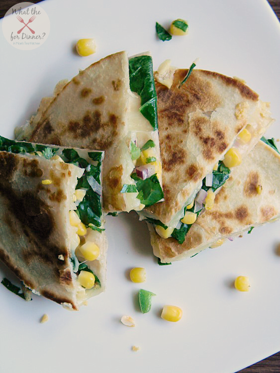 Veggie Quesadillas filled with spinach and corn salsa cut into triangles and stacked on a white plate