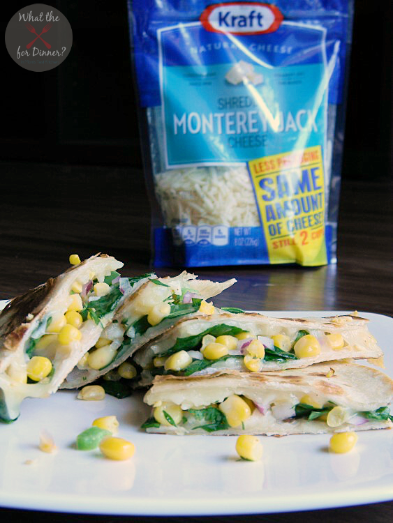 Veggie Quesadillas filled with spinach and corn salsa cut into triangles and stacked on a white plate with a bag of Kraft Monterrey Jack Cheese in the background