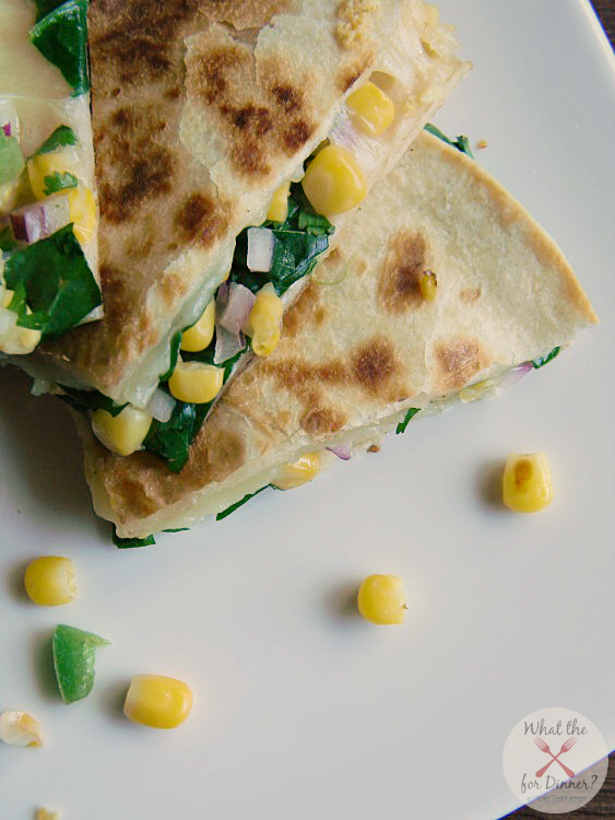 Veggie Quesadillas filled with spinach and corn salsa cut into triangles and stacked on a white plate