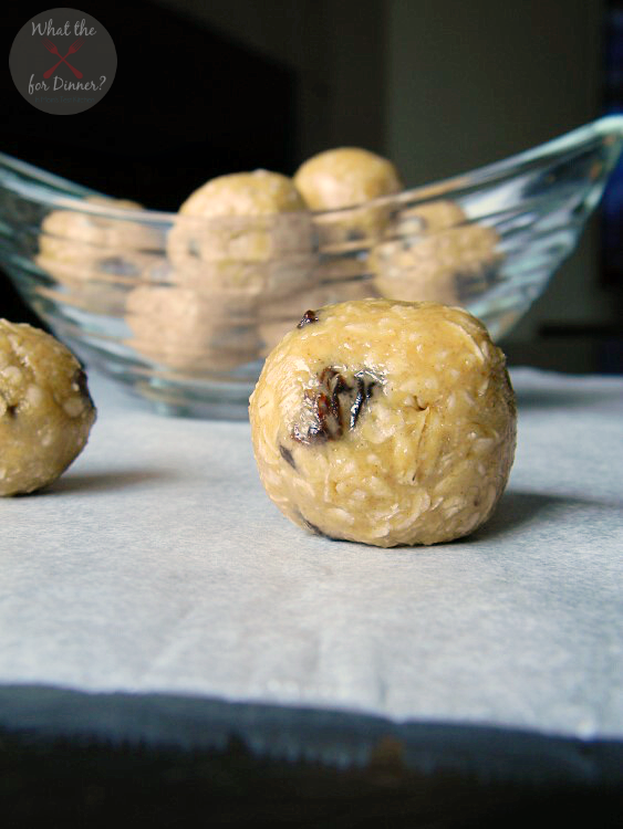 No Bake Energy Ball sitting on a table in the foreground with a clear bowl filled with energy balls in the background
