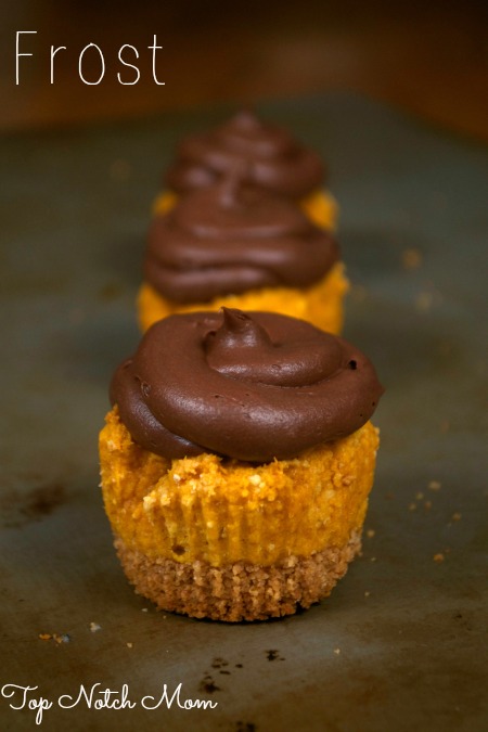 Three Pumpkin S'mores Cupcakes topped with chocolate frosting sitting on a tray