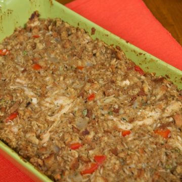 A green baking dish filled with Stuffing Casserole sitting on a red place setting
