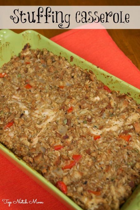 A green baking dish filled with Stuffing Casserole sitting on a red place setting