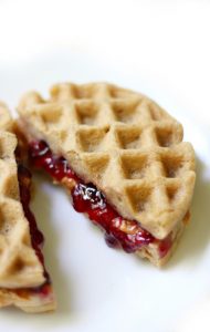 Peanut Butter and Jelly Waffle Sandwich cut in half on a white plate