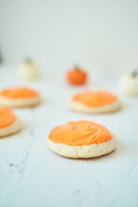 Vanilla Pumpkin Cake Mix Cookies on a white table with small pumpkins in the background