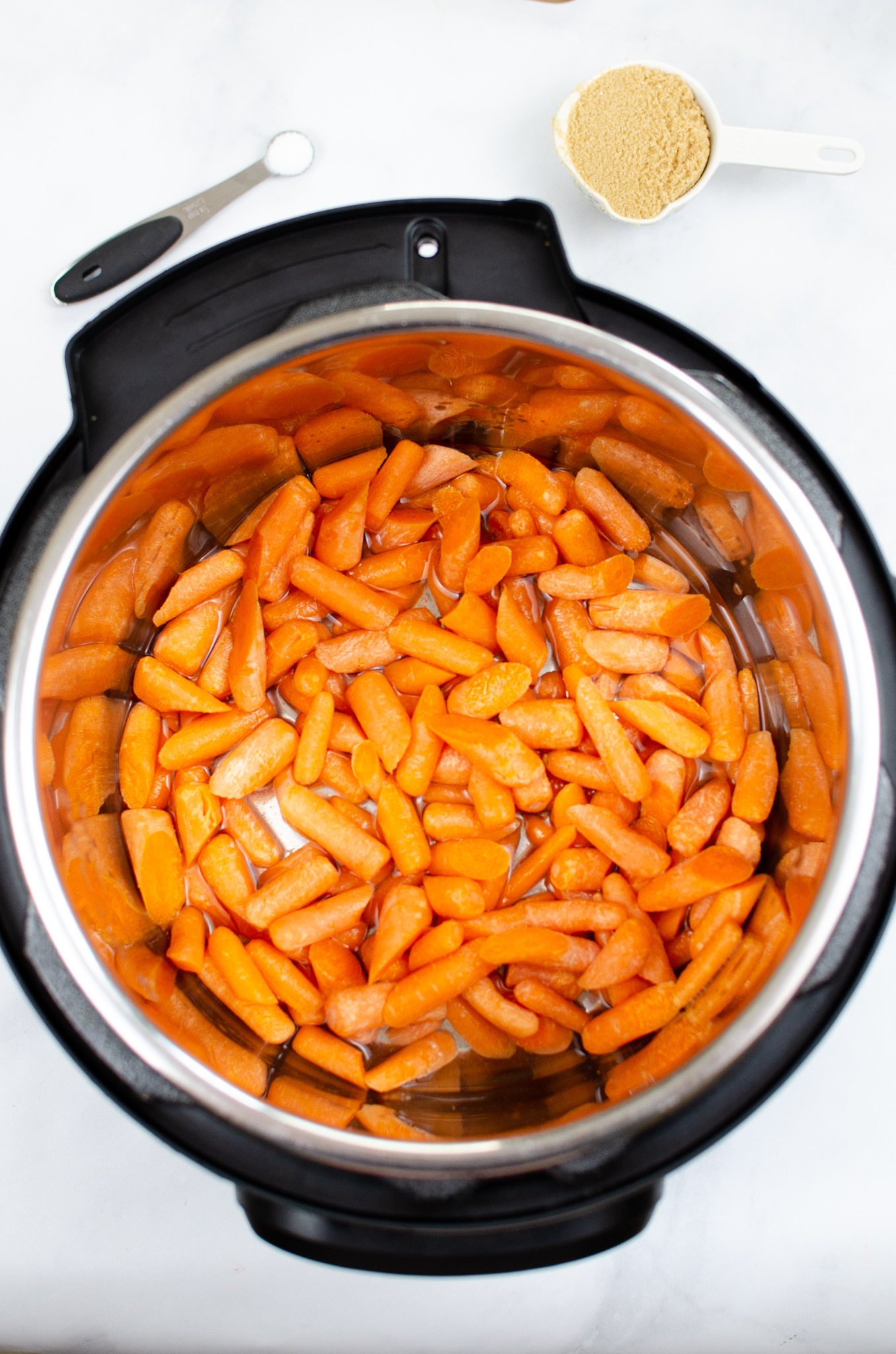 carrots in an instant pot with brown sugar and salt sitting above the Instant pot