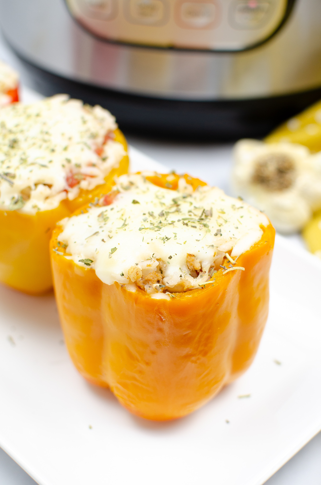 two instant pot stuffed peppers on a white plate with the bottom of the instant pot showing in the background