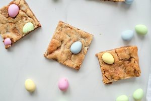 three cookie bars on a white background with extra mini eggs around them