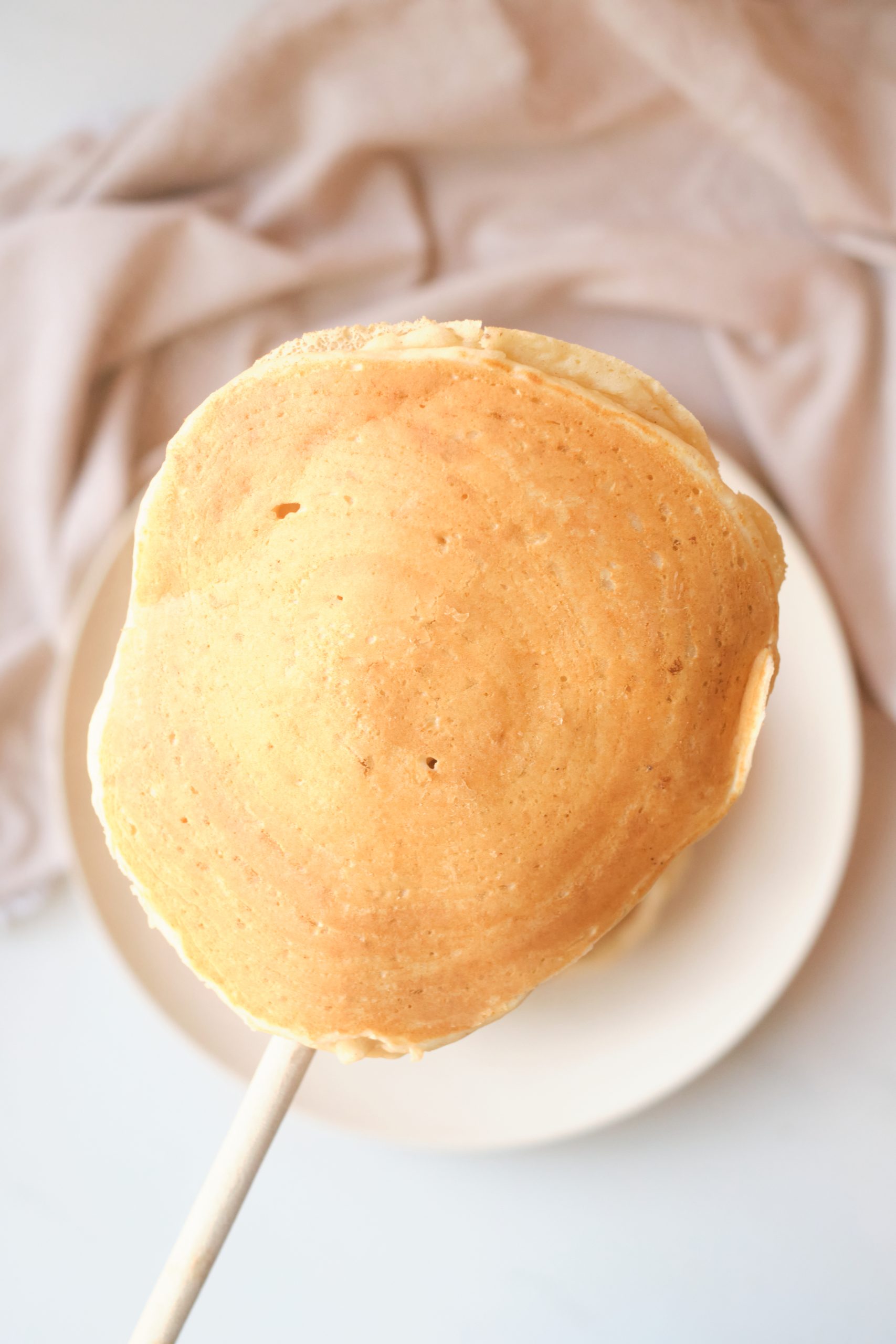 a pancake being flipped with a wooden spoon